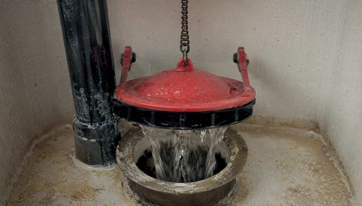 Close-up of lifted toilet flapper valve during flush