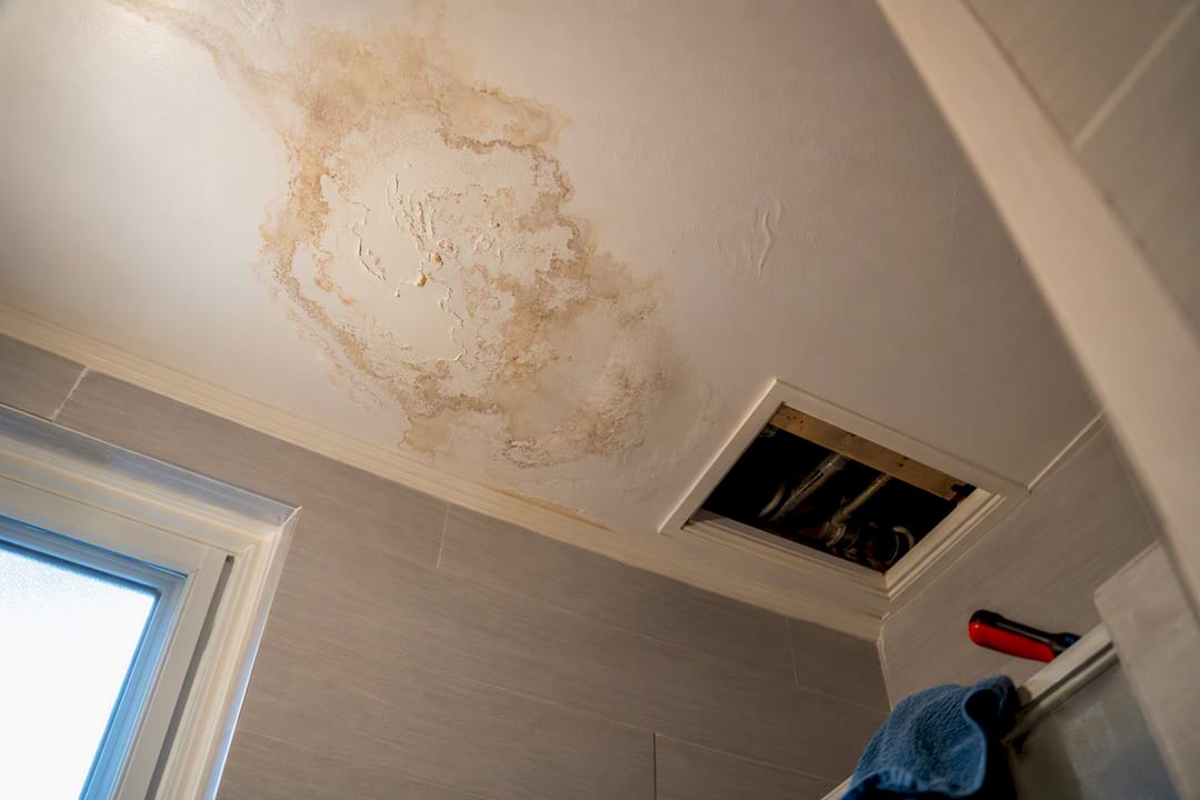 Water stain spreading across bathroom ceiling