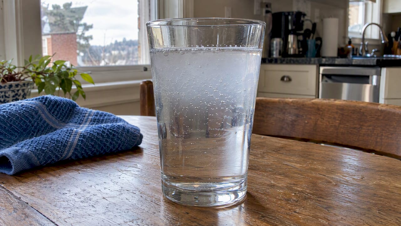Cloudy tap water beginning to clear in a glass